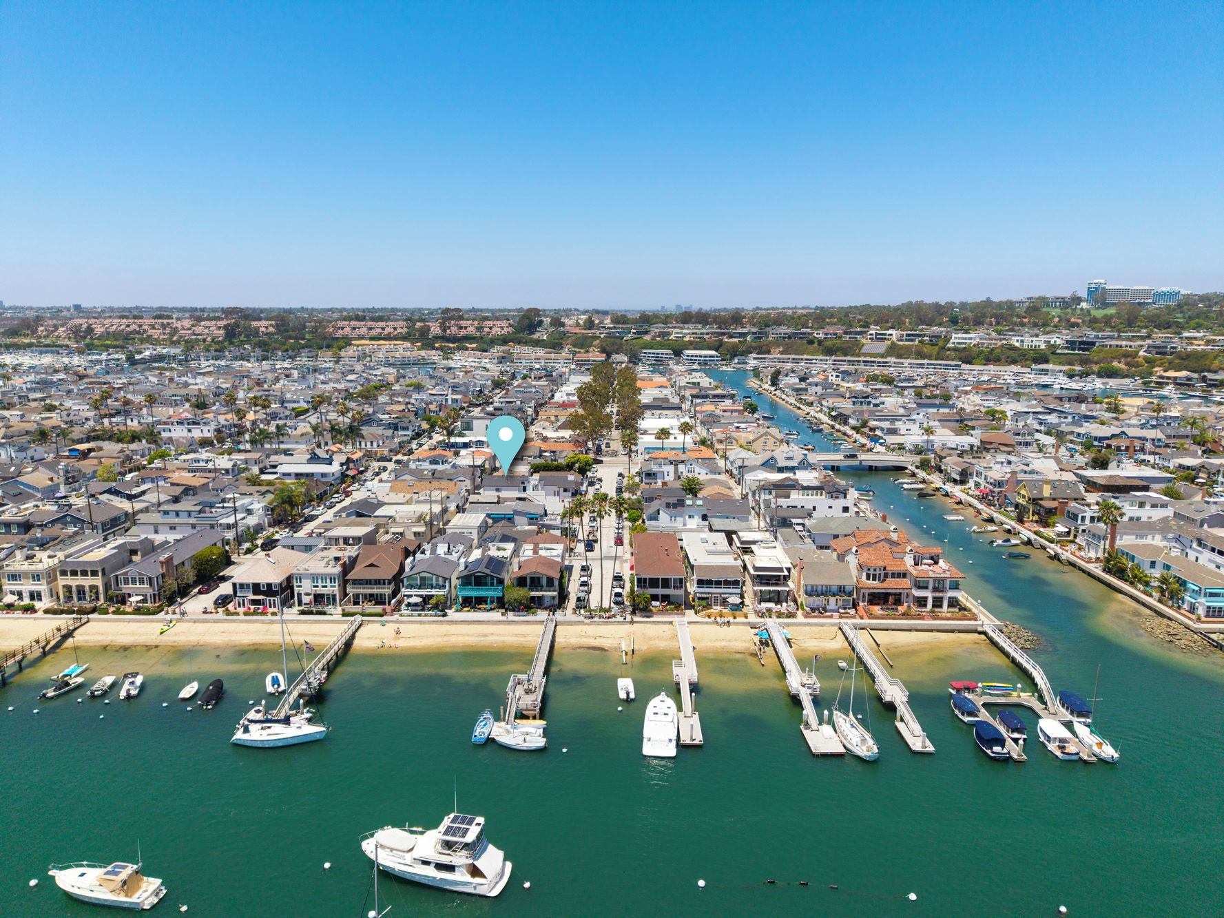 A coastal residential area with a marina, houses, and a clear sky.