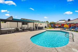 Ein Schwimmbecken mit überdachter Terrasse, Liegestühlen und einer Wandmalerei mit dem Schriftzug 'Las Vegas'.