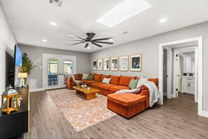 Ein modernes Wohnzimmer mit einer Couch, einem Couchtisch und einem Deckenventilator.