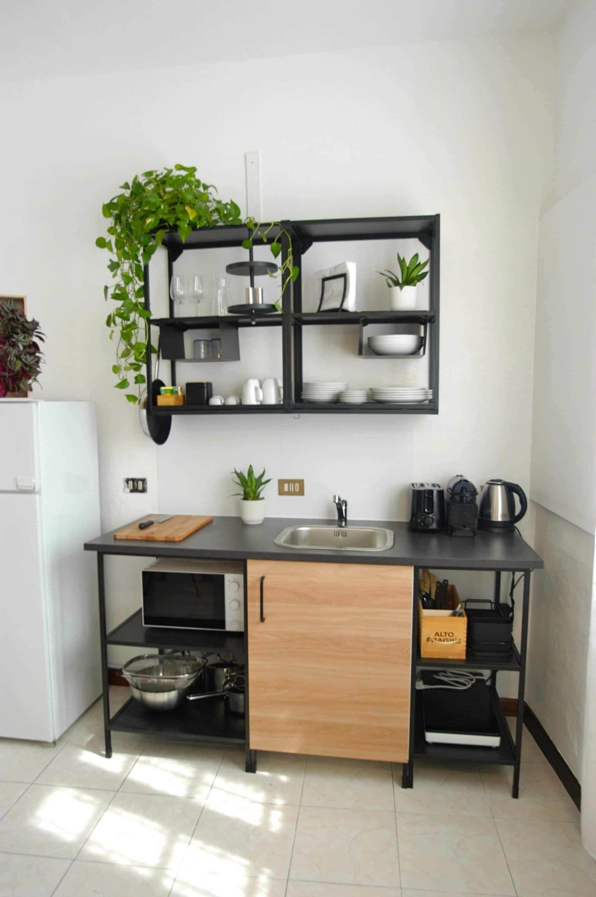 A compact kitchen with a black countertop, a sink, and a wooden cabinet.