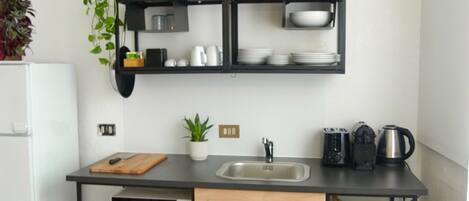 A compact kitchen with a black countertop, a sink, and a wooden cabinet.