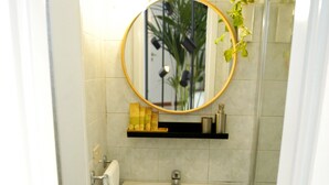 Ein Badezimmer mit einem weißen Waschbecken, einem Spiegel und einer Dusche.
