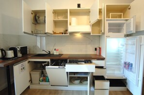 A compact kitchen with a built-in dishwasher, a microwave, and a refrigerator. - Dimora Romana – MARTINI's Home, Milano (Milano)