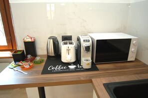 A kitchen counter with a coffee maker, toaster, kettle, and microwave. - Dimora Romana – MARTINI's Home, Milano (Milano)