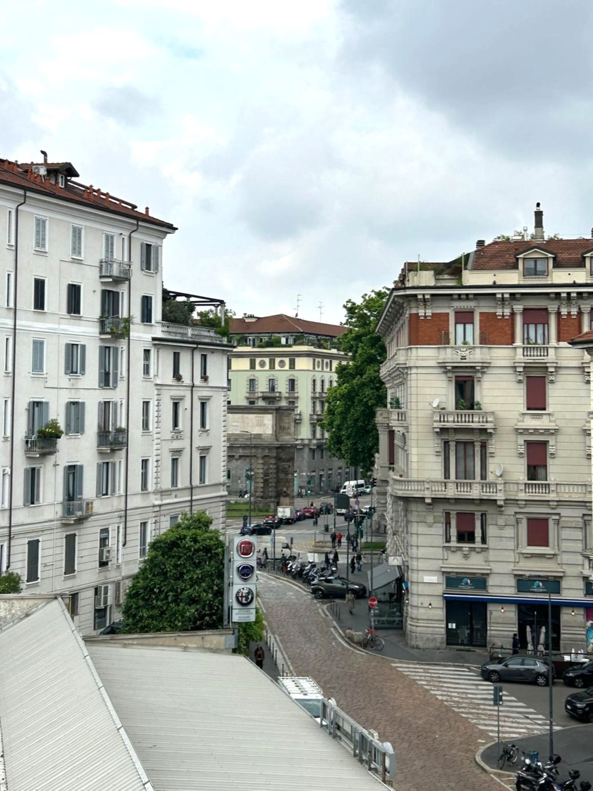 Une vue de rue avec des immeubles à plusieurs étages, un passage piéton et un panneau de signalisation.