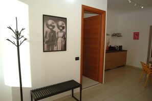 Een kamer met een bank, een deur, een keukenhoek en een lijst met een foto aan de muur.