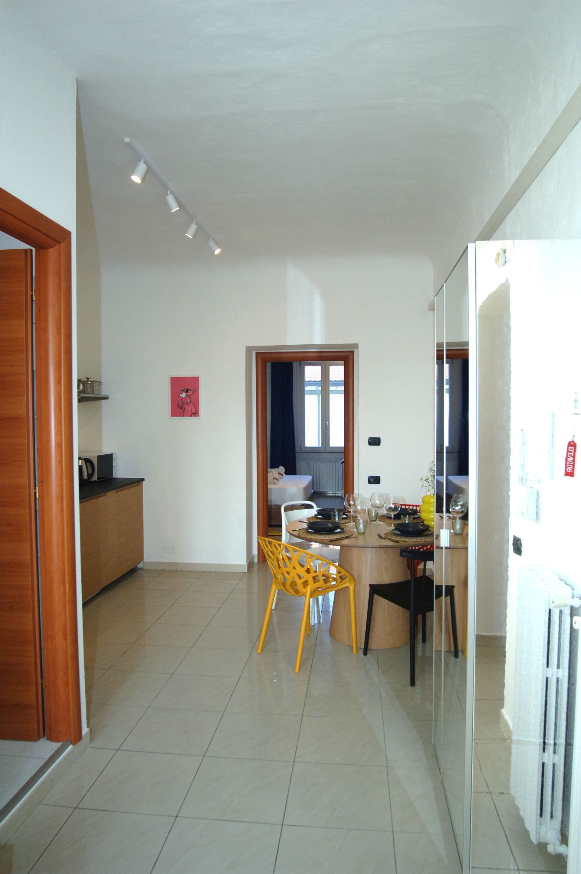 A modern kitchen with a dining area, featuring a refrigerator, a wooden cabinet, and a dining table with chairs.