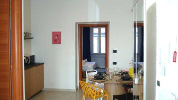 A modern kitchen with a dining area, featuring a refrigerator, a wooden cabinet, and a dining table with chairs.