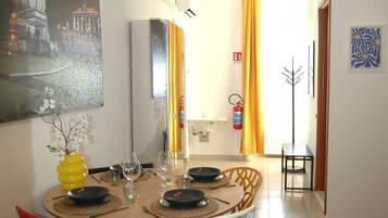 Comedor con una mesa redonda dispuesta para cuatro personas, sillas y un florero con flores.