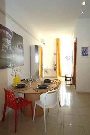 A dining area with a round table set for four, chairs, and a vase with flowers. - Ecletic Jungle - MARTINI'S home (Milano)