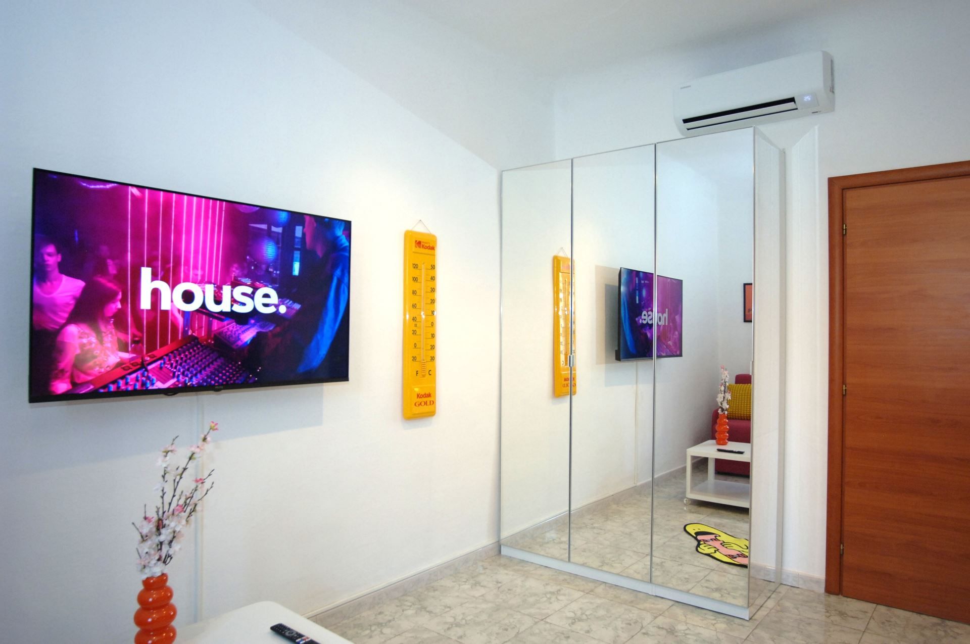 A modern living room with a flat-screen TV, a glass partition, and a wooden door.