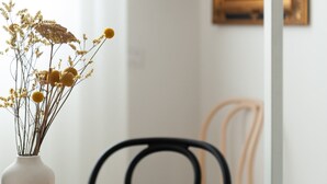 A dining table with a vase of dried flowers, a chair, and a painting on the wall. - Foresteria MILO MARTINI's Home (Milano)