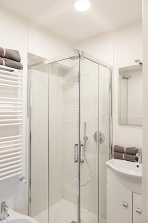 A modern bathroom with a glass-enclosed shower, a white sink, and a mirror above the sink. - Foresteria MILO MARTINI's Home (Milano)