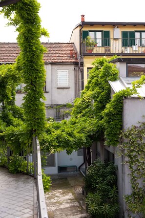 Un callejón estrecho con un edificio a un lado y un árbol con follaje verde al otro.