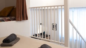 Et hotelværelse med en seng, et vindue med gardiner, udsigt til det fri og en trappe.