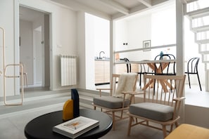 A modern living room with a dining area, a view of the kitchen, and a large window. - Foresteria MILO MARTINI's Home (Milano)