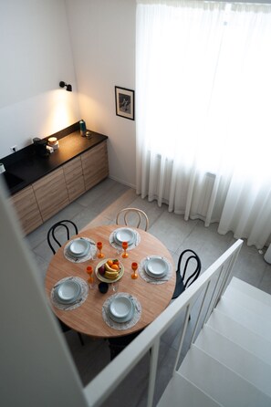 Comedor con una mesa redonda dispuesta para cuatro personas, con platos, vasos y cubiertos.