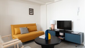 A modern living room with a sofa, a coffee table, a TV, and a lamp. - Foresteria MILO MARTINI's Home (Milano)