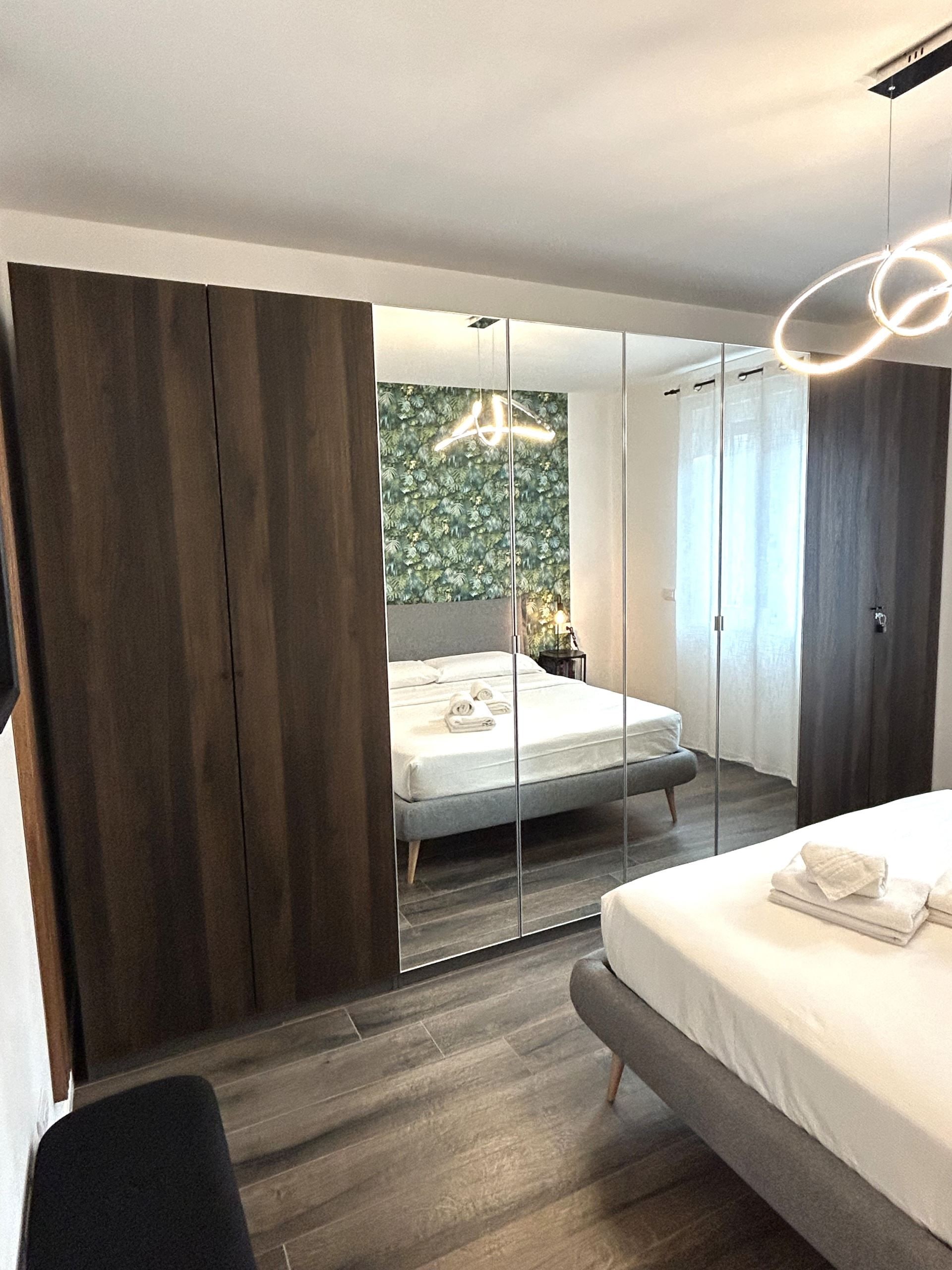 Een moderne slaapkamer met een bed, een spiegel en een kledingkast.
