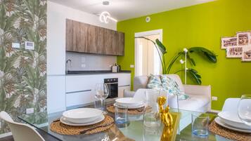 Una cucina moderna con mobili in legno, un'area pranzo con tavolo in vetro e una parete verde brillante.