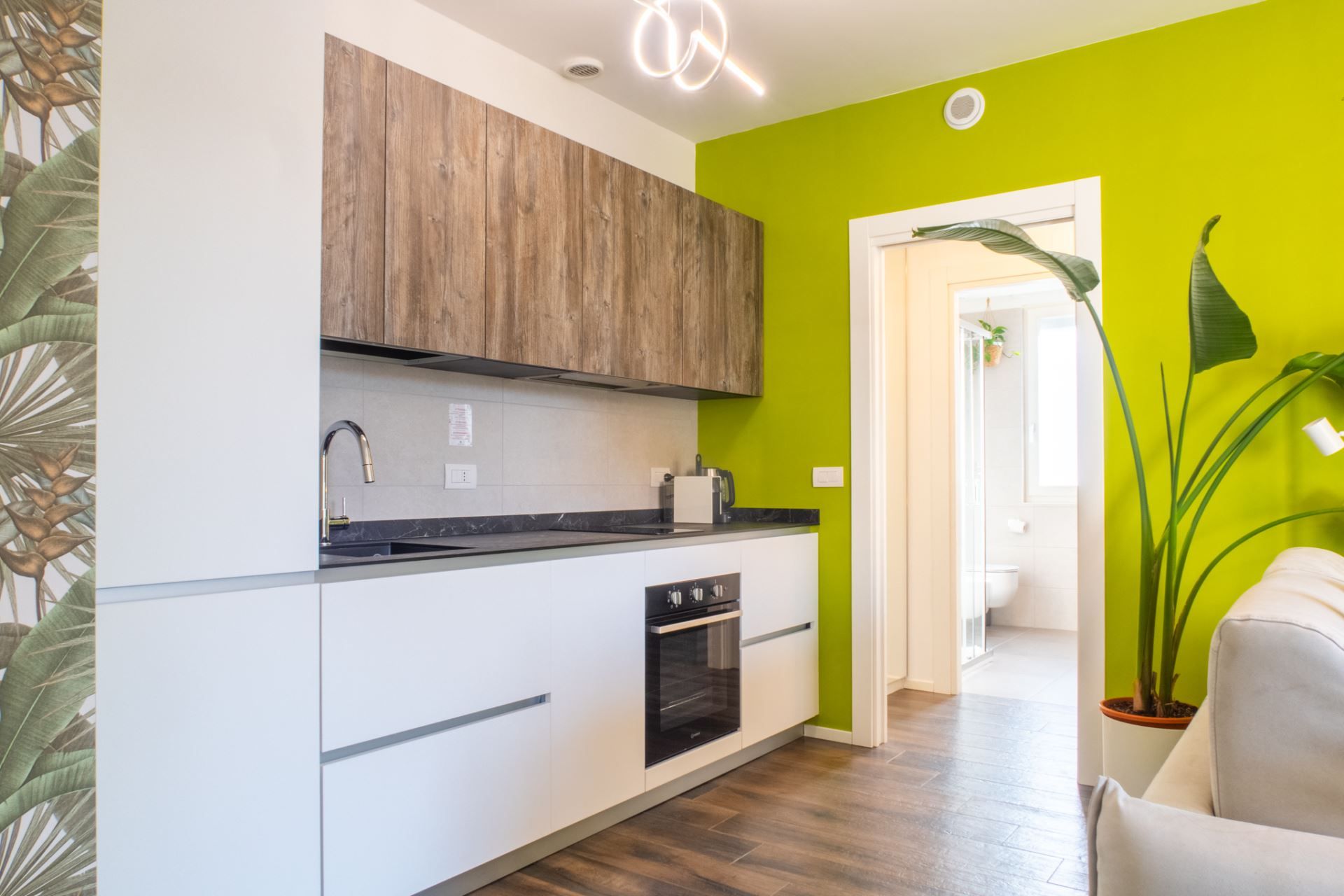 A modern kitchen with white cabinetry, a wooden upper section, and a black countertop.