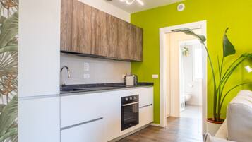 A modern kitchen with white cabinetry, a wooden upper section, and a black countertop.