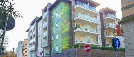 Un edificio residencial de varios pisos con balcones, un cartel de no estacionamiento y un paso de peatones.