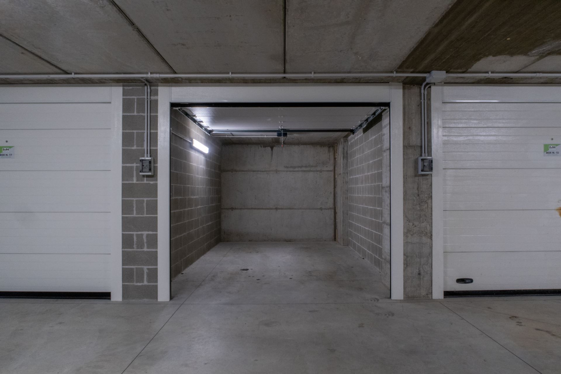 Un étroit puits d’ascenseur, fermé et doté de murs en béton et d’une porte métallique à son extrémité.