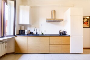 A modern kitchen with a black countertop, stainless steel range hood, and wooden cabinets. - Jasmine House - MARTINI's Home, Milano (Milano)