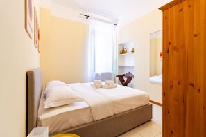 A hotel room with a bed, a wooden wardrobe, a bedside table, and a window with curtains. - Jasmine House - MARTINI's Home, Milano (Milano)