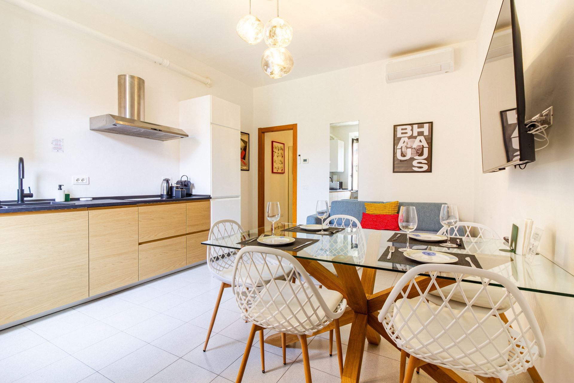 A modern kitchen with a central island, white chairs, and a dining table set for four.