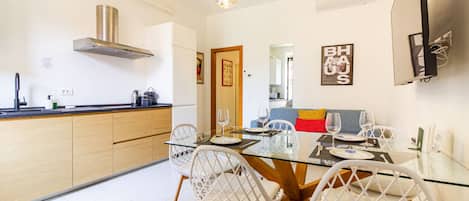 A modern kitchen with a central island, white chairs, and a dining table set for four.