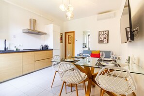 A modern kitchen with a central island, white chairs, and a dining table set for four. - Jasmine House - MARTINI's Home, Milano (Milano)