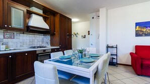 Een moderne keuken met een eetgedeelte, witte stoelen en een rode fauteuil.