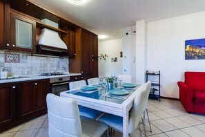 Una cocina moderna con comedor, sillas blancas y un sillón rojo.