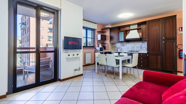 Een modern appartement met een keuken, een eethoek en een rode bank.