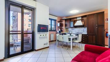 A modern apartment with a kitchen, dining area, and a red sofa.