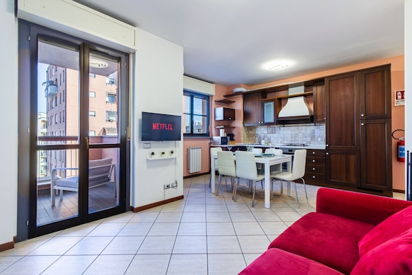 Un apartamento moderno con cocina, comedor y un sofá rojo.