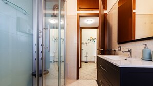 Een moderne badkamer met een douchecabine van glas, een wastafelmeubel en een grote spiegel.
