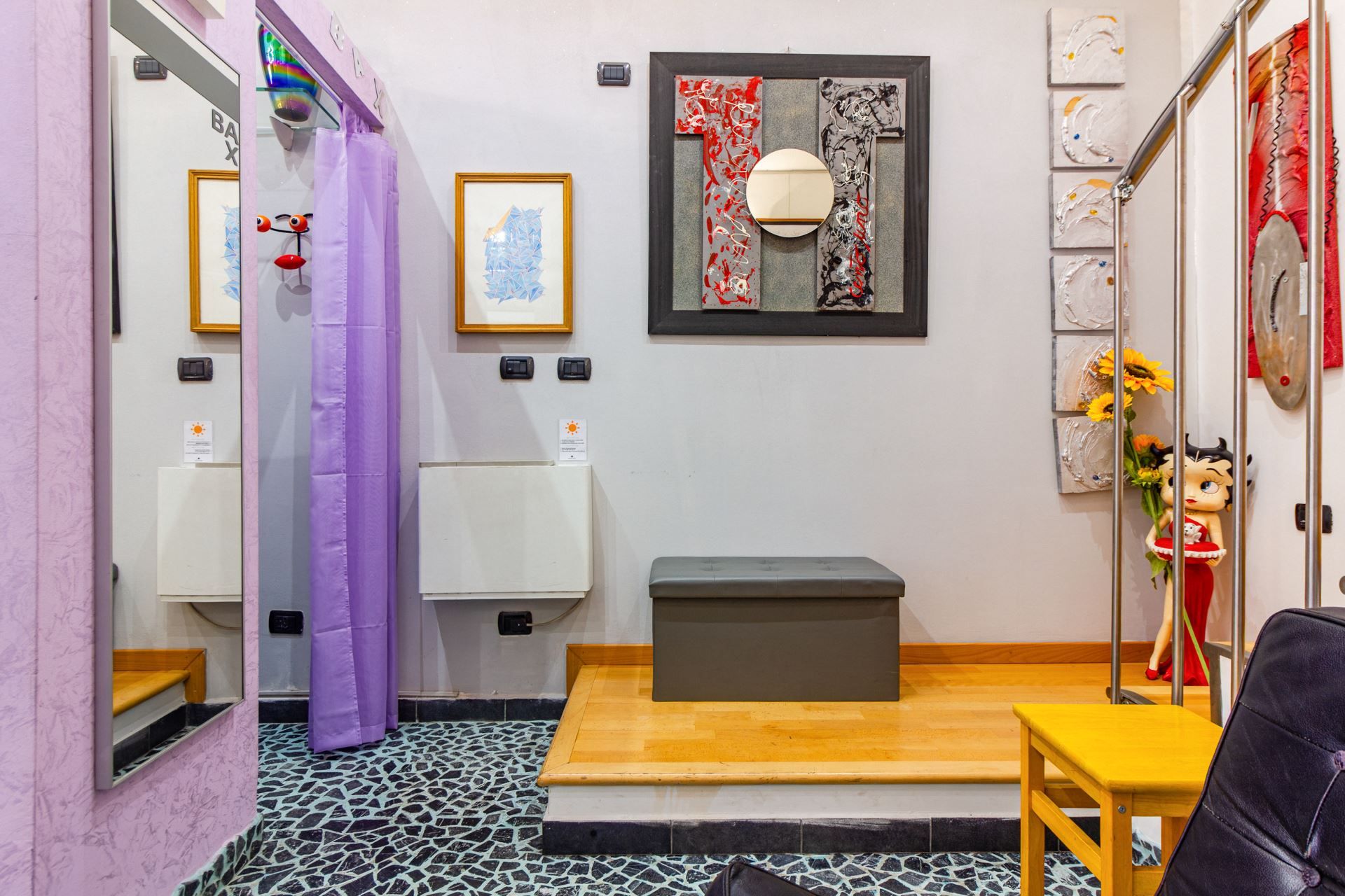 Une salle de bain comprenant un miroir, des toilettes, un lavabo, un banc et une statue décorative.