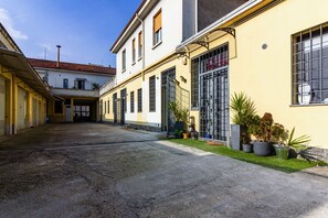 A courtyard with a building featuring large windows and a garage. - Loft Fashion Design - MARTINI's Home, Milano (Sesto San Giovanni)