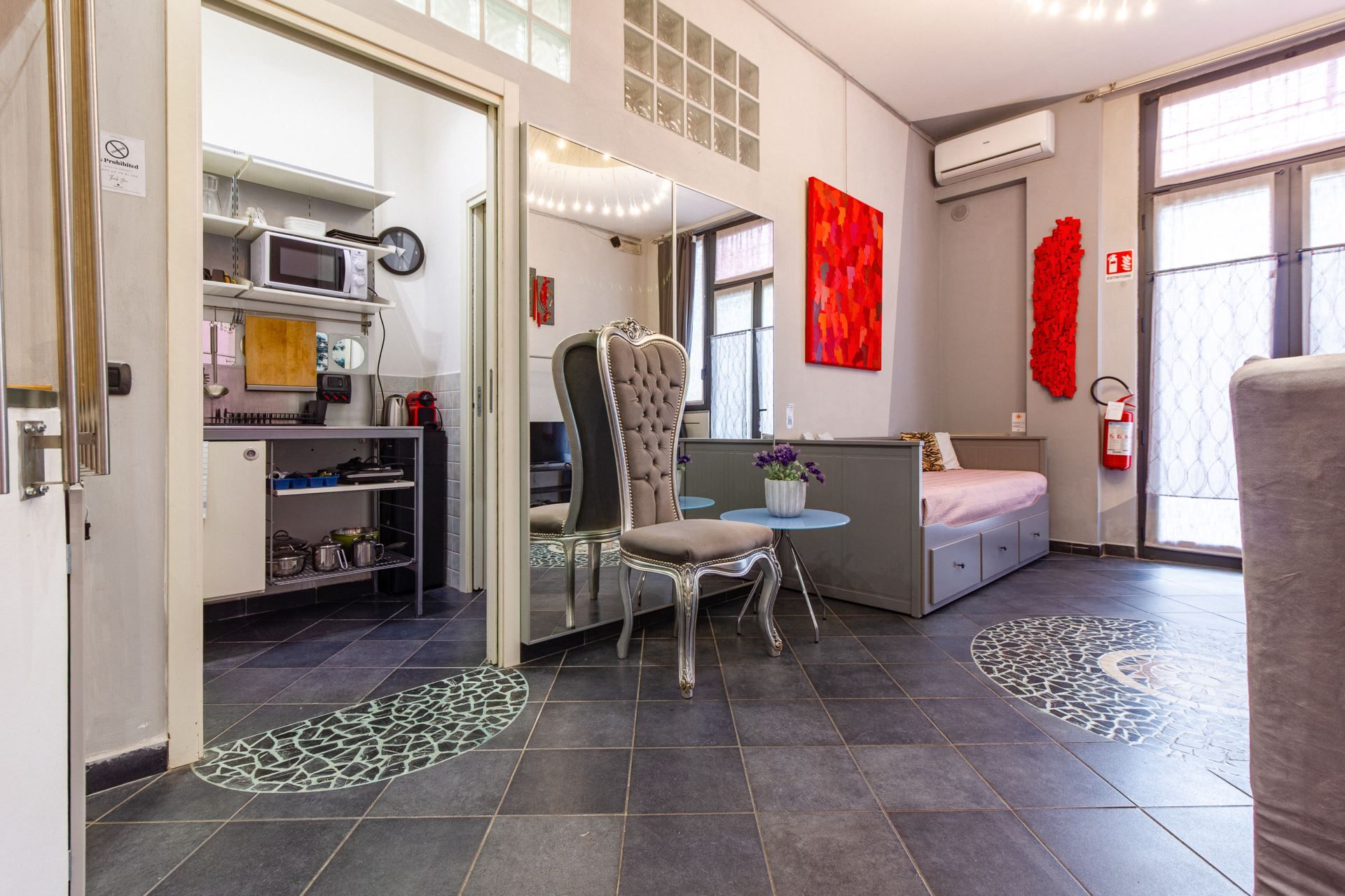 Une chambre d’hôtel moderne dotée d’une kitchenette, d’un coin repas, d’un grand miroir et d’un lit avec vue.