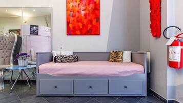 Een moderne hotelkamer met een bed, een bureau en een stoel. Aan de muur hangt een rode brandblusser.