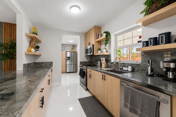 A modern kitchen with a stainless steel refrigerator, a microwave, and a coffee maker. - Luxury 5BR Heated Pool, Game Room, Sandy Beach Area & Basketball (Miami)