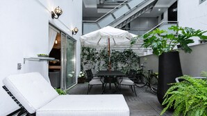 Eine moderne Außenpatio mit einer Liege, einem Esstisch und einem Sonnenschirm.