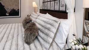 Ein Schlafzimmer mit einem großen Bett, einem Baldachin, einem gerahmten Kunstwerk und einem Nachttisch mit Lampe.
