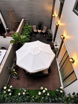 An outdoor patio with a table and umbrella, surrounded by plants and a bicycle. - CONDESA Two Bedroom, Pool, Gym Security 24/7 for group of 6. (Ciudad de México)