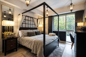 A four-poster bed with a canopy, bedside lamps, a nightstand with a lamp, and a view of greenery outside. - CONDESA Two Bedroom, Pool, Gym Security 24/7 for group of 6. (Ciudad de México)