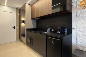 A modern kitchen with a built-in dishwasher, a stove, and a sink. - Studio Le Jardin Cyrela · Pinheiros · Oscar Freire Metro Station (São Paulo)