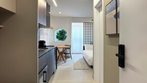 A modern kitchen with a dining area, a large window, and a bed in the adjacent room. - Vrbo Property (São Paulo)